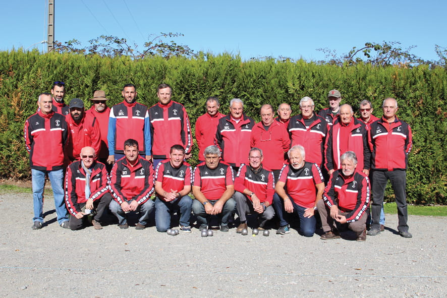 Les membres de l'association de pétanque posant devant une haie.